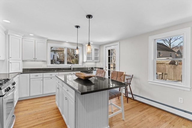 kitchen with white cabinets, glass insert cabinets, a breakfast bar, a center island, and baseboard heating