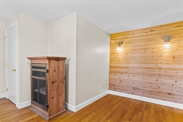 interior space with baseboards, wooden walls, and light wood-style floors