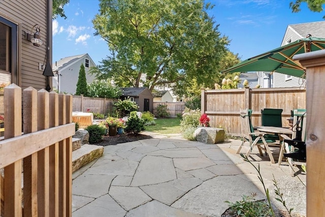 view of patio featuring an outbuilding, a shed, outdoor dining space, and a fenced backyard