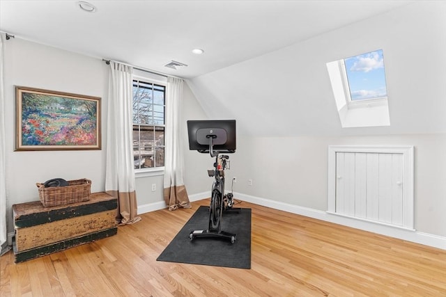 workout room featuring vaulted ceiling with skylight, recessed lighting, wood finished floors, visible vents, and baseboards