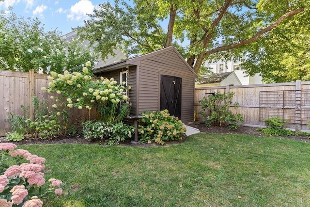 view of yard with a fenced backyard, a storage unit, and an outbuilding