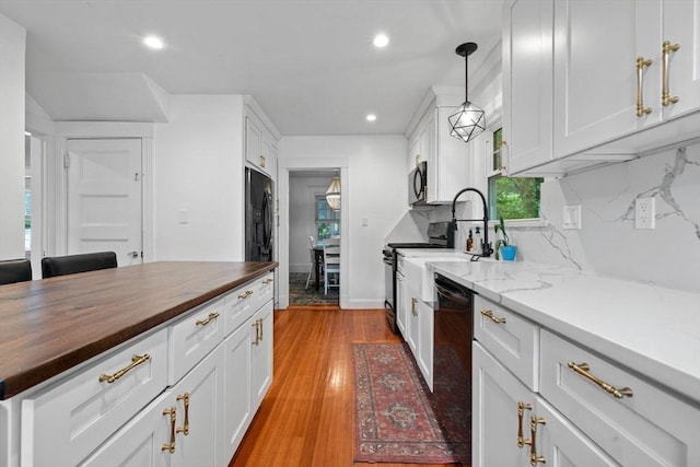 121 W St, Braintree, MA 02184 - kitchen with butcher block counters, black appliances, healthy amount of natural light, white cabinets, and recessed lighting