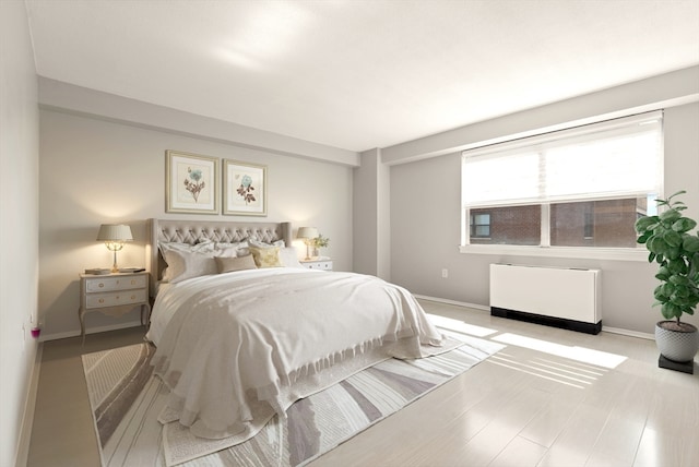 bedroom with radiator heating unit and light hardwood / wood-style flooring