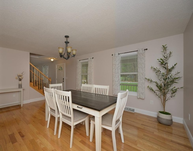 dining space with visible vents, baseboards, stairway, light wood-style flooring, and a notable chandelier