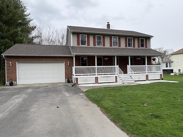 view of front of house with covered porch, driveway, a chimney, a front yard, and a garage