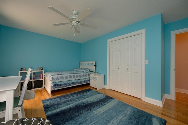 bedroom featuring baseboards, ceiling fan, wood finished floors, and a closet