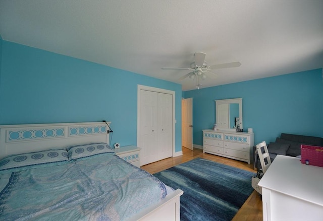 bedroom with a closet, a ceiling fan, baseboards, and wood finished floors