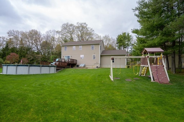 back of property with a lawn, a playground, an outdoor pool, and a deck
