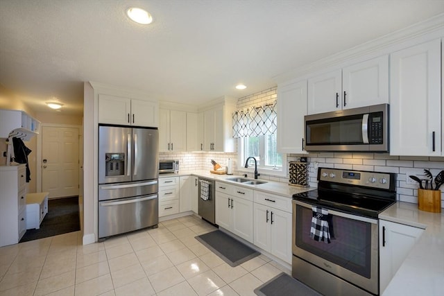 kitchen featuring a sink, appliances with stainless steel finishes, white cabinets, and light countertops