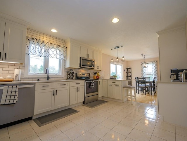 kitchen featuring stainless steel appliances, white cabinetry, a peninsula, light tile patterned floors, and tasteful backsplash