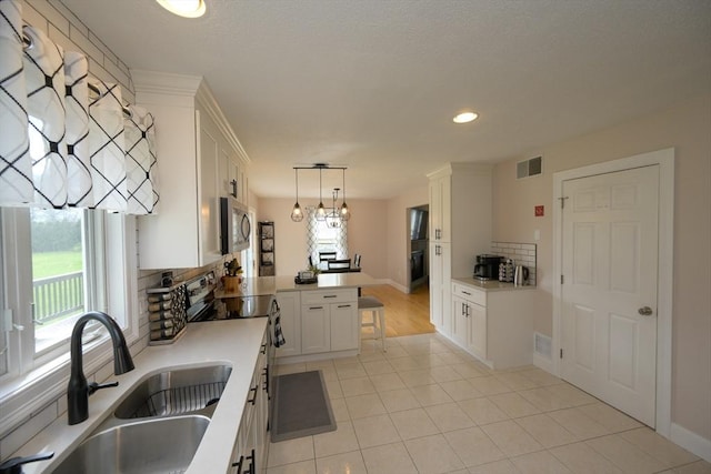 kitchen with visible vents, electric range, a peninsula, stainless steel microwave, and a sink