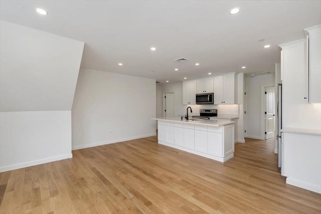 106 Broadway, Salem, MA 01970 - kitchen with stainless steel appliances, a sink, light countertops, white cabinetry, and a center island with sink