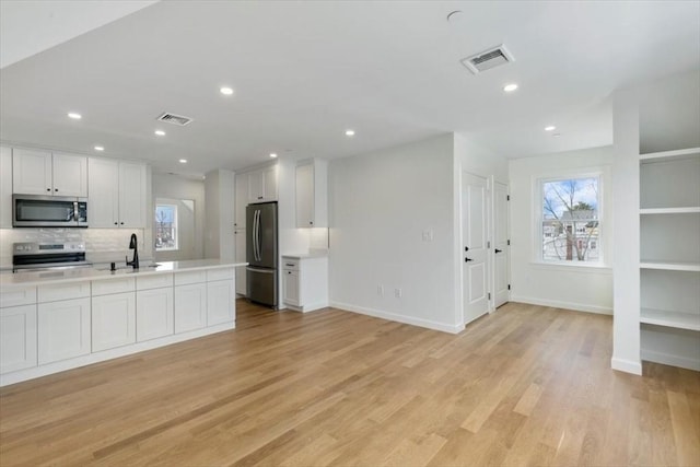 106 Broadway, Salem, MA 01970 - kitchen with stainless steel appliances, a sink, white cabinets, light countertops, and baseboards