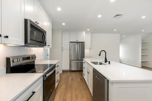 106 Broadway, Salem, MA 01970 - kitchen with stainless steel appliances, a sink, light wood-style flooring, backsplash, and white cabinets