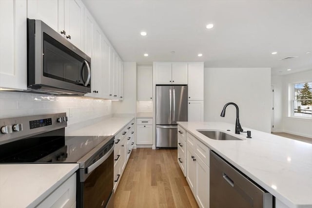 106 Broadway, Salem, MA 01970 - kitchen featuring appliances with stainless steel finishes, a sink, light wood-style flooring, recessed lighting, and decorative backsplash