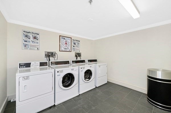 laundry room featuring dark tile patterned floors, washer and clothes dryer, and ornamental molding