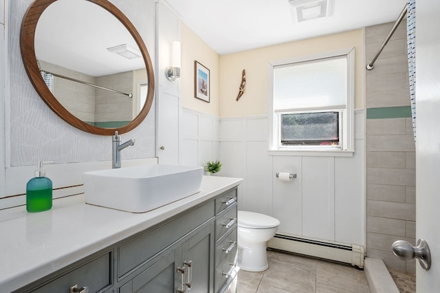 bathroom with a baseboard heating unit, a tile shower, toilet, vanity, and tile patterned floors