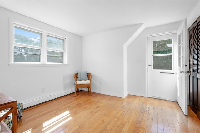 living area with a baseboard radiator and light hardwood / wood-style flooring