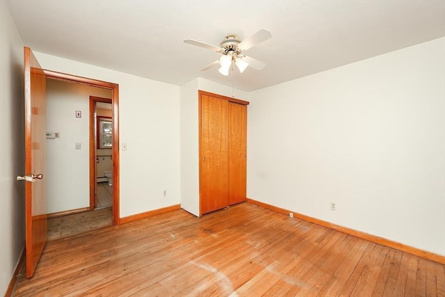 unfurnished bedroom with baseboards, light wood finished floors, ceiling fan, a closet, and baseboard heating