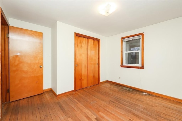 unfurnished bedroom featuring a closet, baseboards, and light wood finished floors