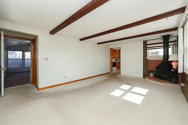 unfurnished living room with beam ceiling, a wood stove, baseboards, and carpet floors