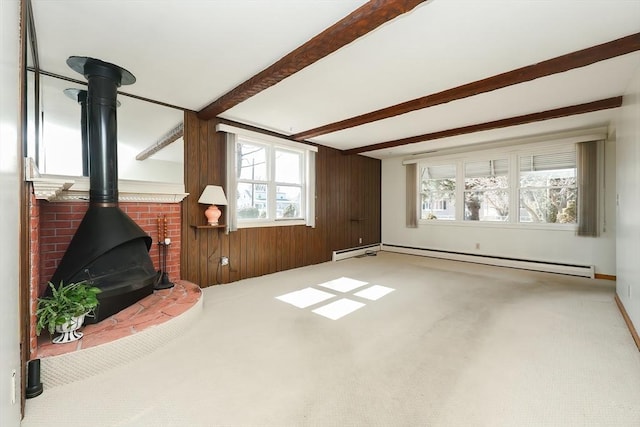 living room with beam ceiling, wooden walls, carpet flooring, baseboard heating, and a wood stove