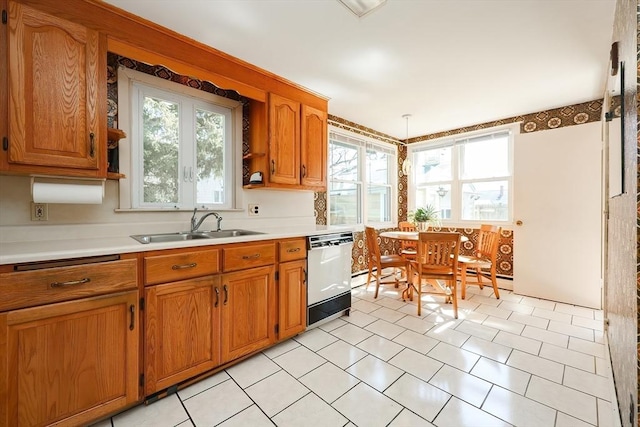 kitchen featuring light countertops, brown cabinets, white dishwasher, and a sink