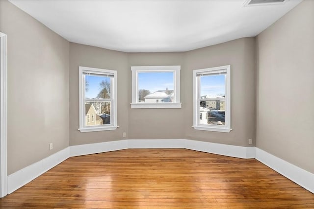 spare room with a healthy amount of sunlight, light wood-style flooring, and baseboards