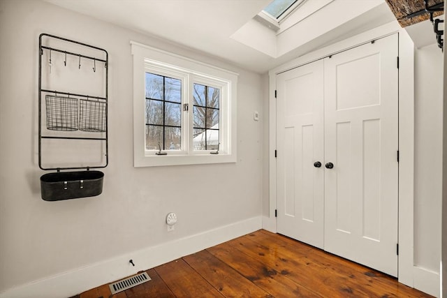 interior space with a skylight, baseboards, visible vents, and hardwood / wood-style floors