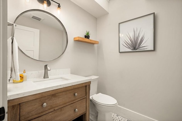 bathroom featuring toilet, vanity, visible vents, and baseboards