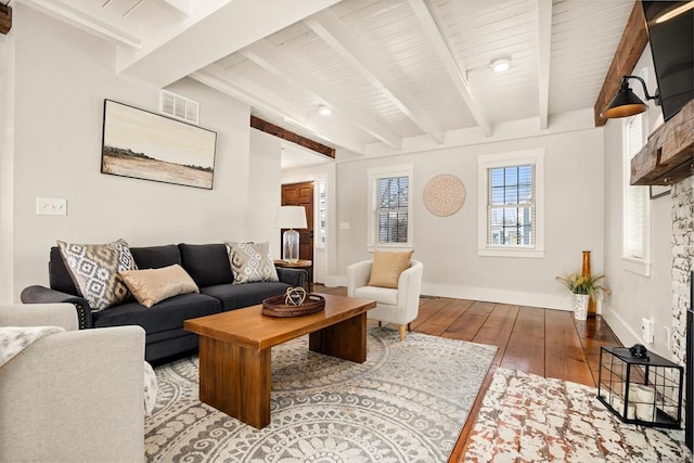 living room with beam ceiling, visible vents, baseboards, and hardwood / wood-style floors