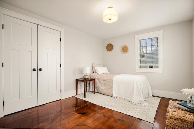 bedroom featuring a closet, dark wood finished floors, and baseboards