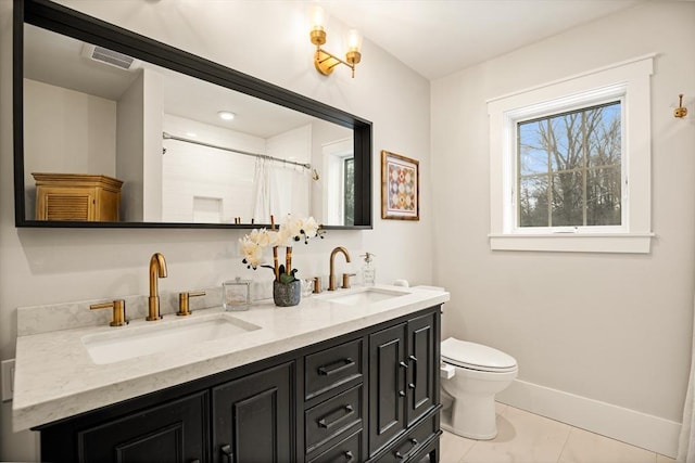 bathroom featuring double vanity, a sink, toilet, and baseboards