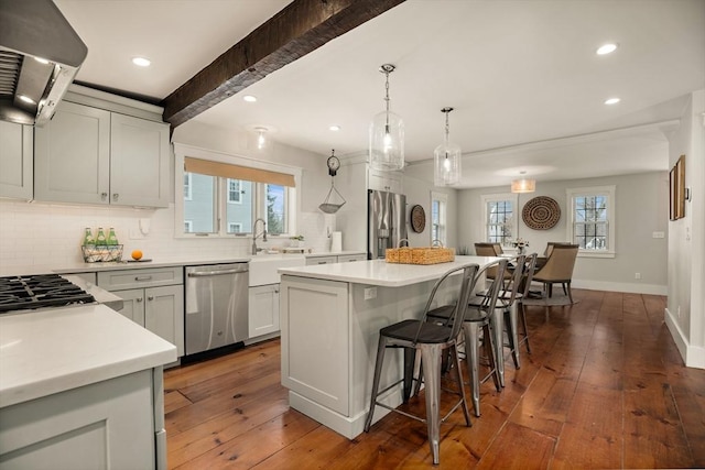 kitchen with dark wood-style floors, a kitchen island, a breakfast bar, extractor fan, and stainless steel appliances