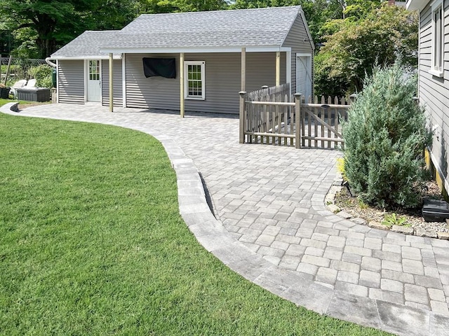 view of front of home featuring a patio area, fence, a front lawn, and roof with shingles