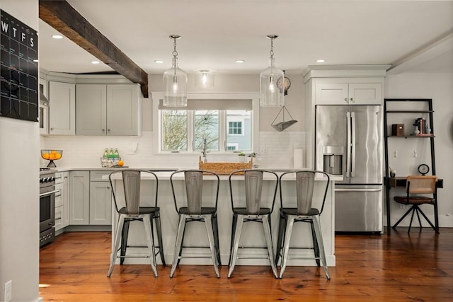 kitchen featuring stainless steel appliances, a kitchen breakfast bar, light countertops, dark wood-style floors, and pendant lighting