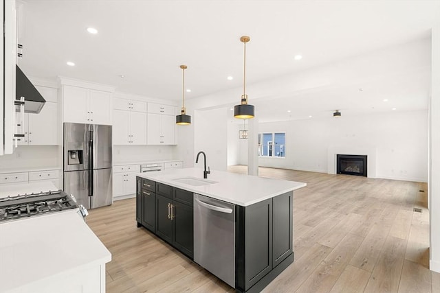 kitchen featuring pendant lighting, an island with sink, stainless steel appliances, and sink