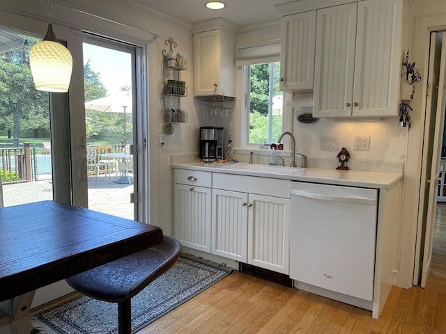 kitchen featuring a sink, light wood-type flooring, crown molding, light countertops, and dishwasher