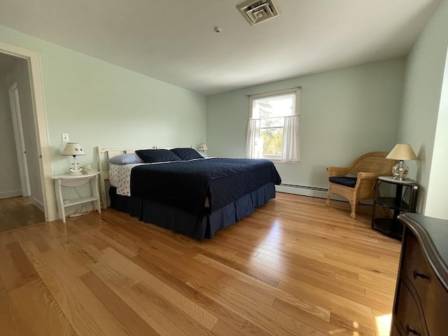 bedroom featuring a baseboard radiator, visible vents, and light wood-style flooring