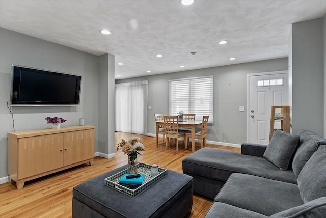 living area with recessed lighting, baseboards, and light wood-style flooring