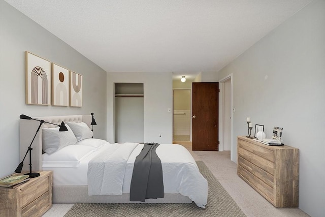 bedroom with ensuite bath, light colored carpet, and a closet