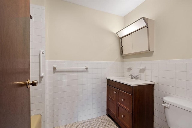 full bathroom featuring wainscoting, vanity, toilet, and tile walls