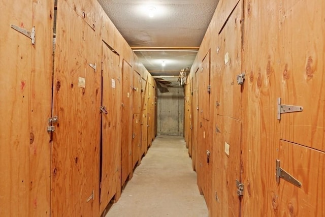 hallway featuring wooden walls, concrete flooring, and a textured ceiling