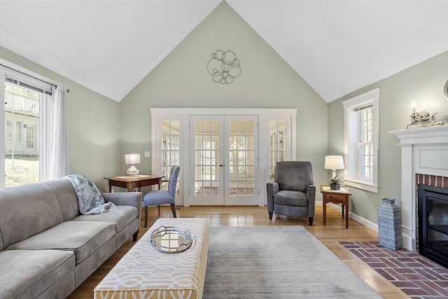 living area featuring a brick fireplace, high vaulted ceiling, a wealth of natural light, and french doors