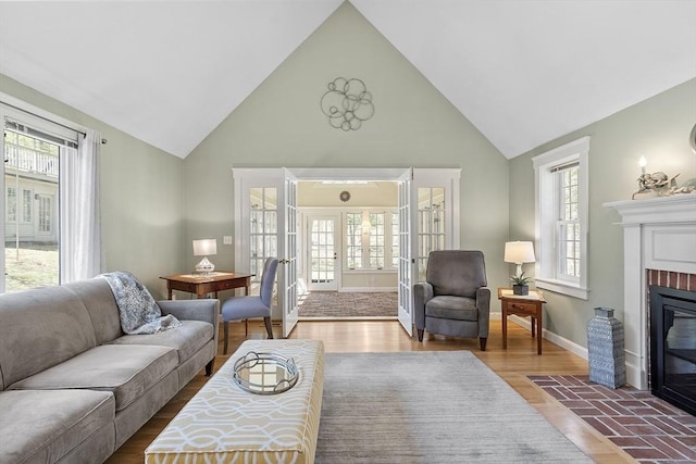 living room featuring baseboards, a brick fireplace, wood finished floors, and high vaulted ceiling