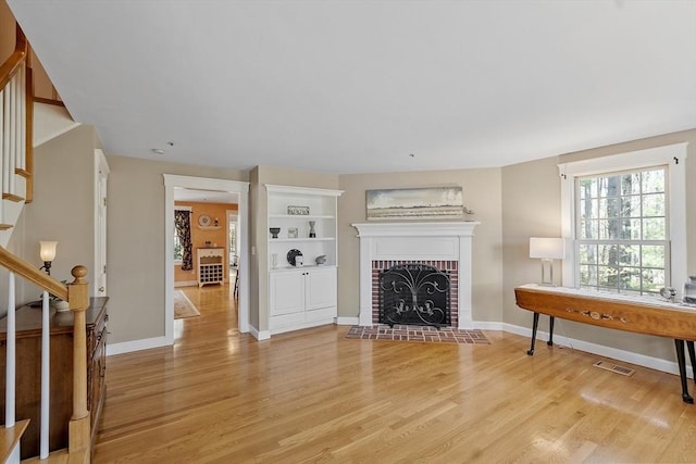 living room with baseboards, stairs, light wood-style flooring, and visible vents