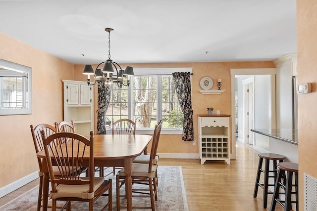 dining area with an inviting chandelier, baseboards, and light wood-style floors