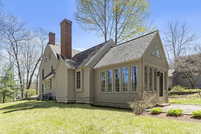 back of house with a lawn, cooling unit, and a chimney