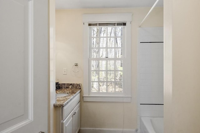 bathroom featuring vanity, baseboards, and bathtub / shower combination