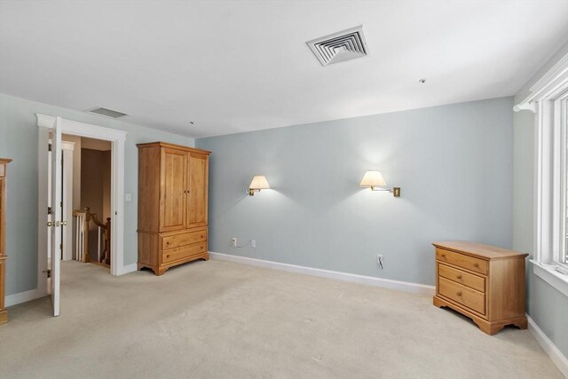 unfurnished bedroom featuring baseboards, light carpet, and visible vents